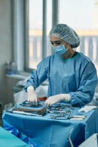 An image of a surgeon preparing her tools illustrates the risks of trusting penis surgery for permanent penis enlargement.