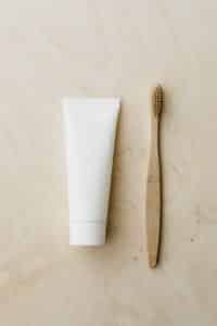 A white tube containing permanent male enlargement cream & bamboo toothbrush