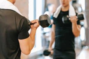 A photo of men in a gym demonstrates that exercise is one of the ways for a man to get better in bed.