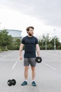 An image of a man lifting some weights, light weightlifting can help you get better in bed.