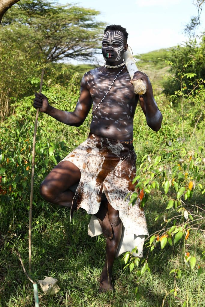 The intriguing image of a male traditional healer adorned in ceremonial garb as he prepares to cast potent spells for penis growth